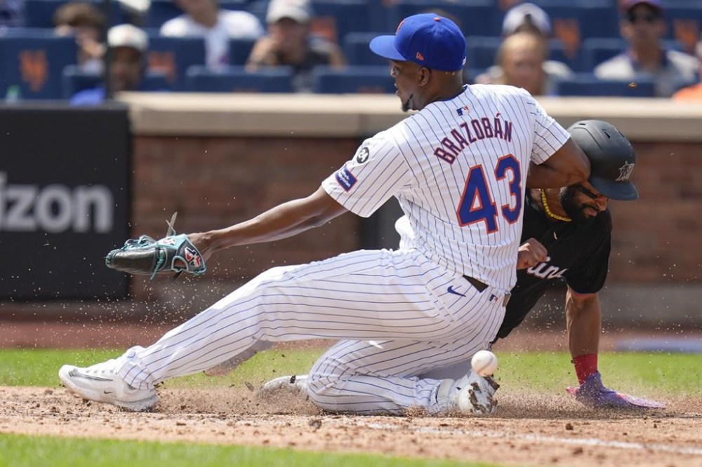 Miami Marlins' Derek Hill, right, scores past New York Mets pitcher Huascar Brazobán (43) after a wild pitch during the seventh inning of a baseball game at Citi Field, Sunday, Aug. 18, 2024, in New York. (AP Photo/Seth Wenig)