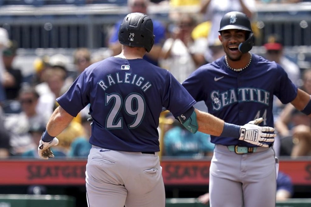 Seattle Mariners' Cal Raleigh, left, is greeted by Julio Rodriguez, right, after hitting a two-run home run during the first inning of a baseball game against the Pittsburgh Pirates, Sunday, Aug. 18, 2024, in Pittsburgh. (AP Photo/Matt Freed)