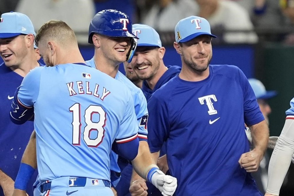 Texas Rangers' Carson Kelly (18), Josh Jung, center, and Max Scherzer, right, celebrate in the 10th inning of a baseball game after the team's 6-5 win against the Minnesota Twins, Sunday, Aug. 18, 2024, in Arlington, Texas. (AP Photo/Tony Gutierrez)