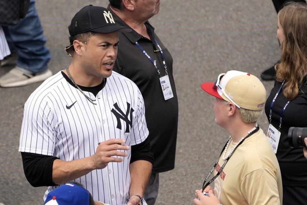 New York Yankees' Giancarlo Stanton walks in talking with Henderson, Nev.'s Oliver Johnson as the New York Yankees arrive at the Little League World Series Complex to watch the Little League World Series tournament in South Williamsport, Pa., Sunday, Aug. 18, 2024. (AP Photo/Tom E. Puskar)
