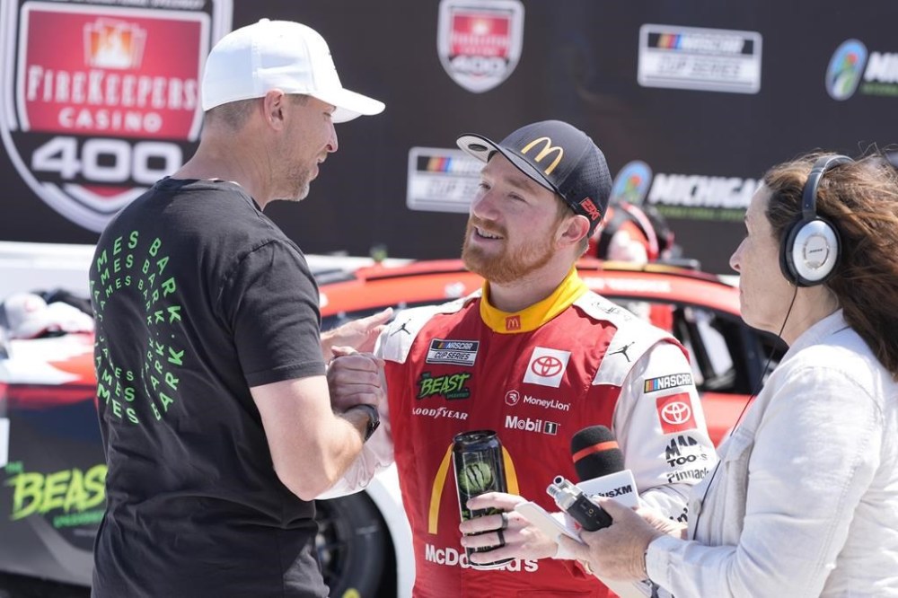 Tyler Reddick is greeted by Denny Hamlin after winning a NASCAR Cup Series auto race at Michigan International Speedway, Monday, Aug. 19, 2024, in Brooklyn, Mich. (AP Photo/Carlos Osorio)