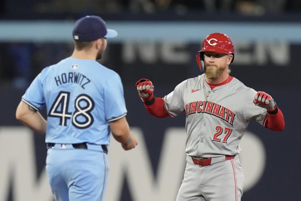Cincinnati Reds Jake Fraley celebrates in front of Toronto Blue Jays Spencer Horwitz after hitting an RBI double during sixth inning Interleague MLB baseball action in Toronto on Monday Aug. 19, 2024. THE CANADIAN PRESS/Chris Young