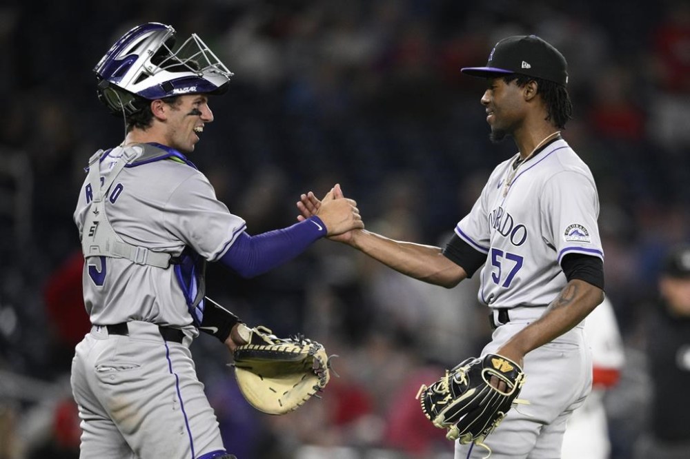 Colorado Rockies relief pitcher Angel Chivilli, right, and catcher Drew Romo, left, celebrate after a baseball game against the Washington Nationals, Tuesday, Aug. 20, 2024, in Washington. The Rockies won 3-1. (AP Photo/Nick Wass)