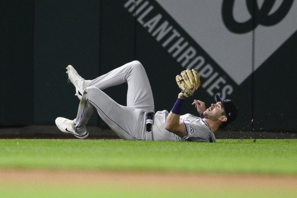 Colorado Rockies left fielder Nolan Jones slides on the grass after he caught a fly ball by Washington Nationals' Andres Chaparro for the out during the eighth inning of a baseball game, Tuesday, Aug. 20, 2024, in Washington. The Rockies won 3-1. (AP Photo/Nick Wass)