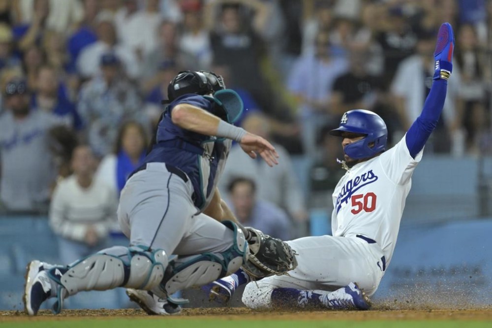 Los Angeles Dodgers' Mookie Betts (50) is tagged out at home by Seattle Mariners' Cal Raleigh in the seventh inning of a baseball game Tuesday, Aug. 20, 2024, in Los Angeles. (AP Photo/Jayne-Kamin-Oncea)