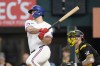 Texas Rangers' Wyatt Langford follows through on a run-scoring single as Pittsburgh Pirates catcher Yasmani Grandal, right, looks on in the ninth inning of a baseball game, Wednesday, Aug. 21, 2024, in Arlington, Texas. (AP Photo/Tony Gutierrez)