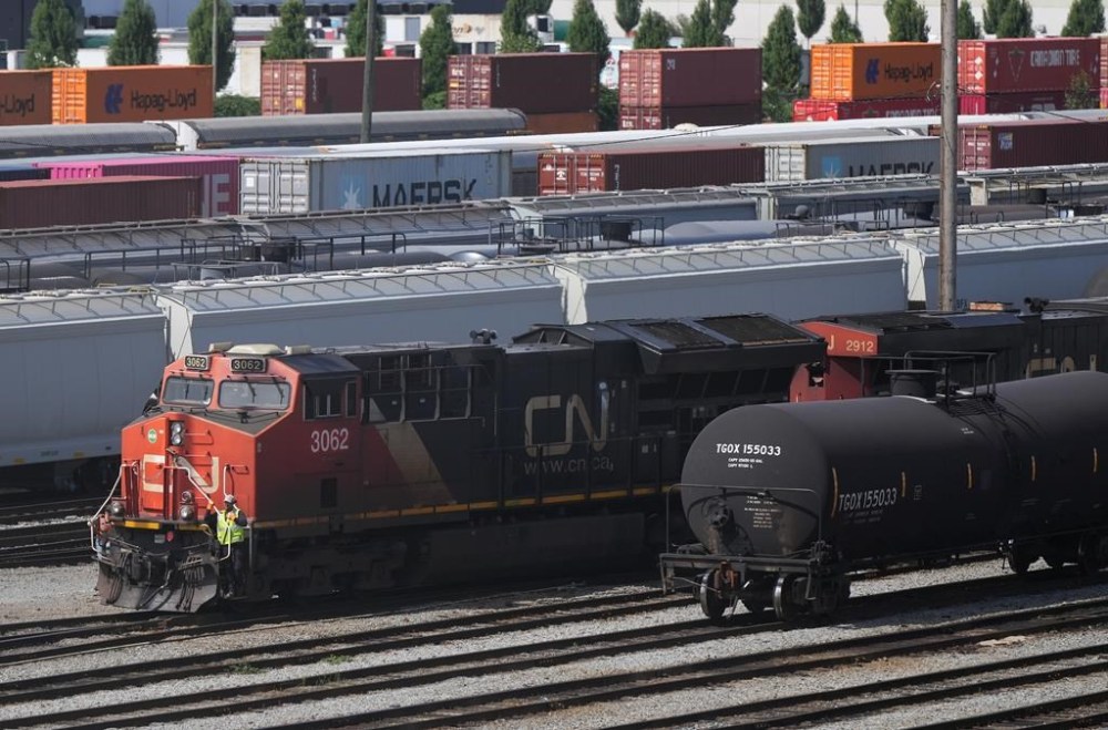 Employees are seen on a locomotive being moved at the Canadian Pacific Kansas City (CPKC) rail yard in Port Coquitlam, B.C., Monday, Aug. 19, 2024. THE CANADIAN PRESS/Darryl Dyck