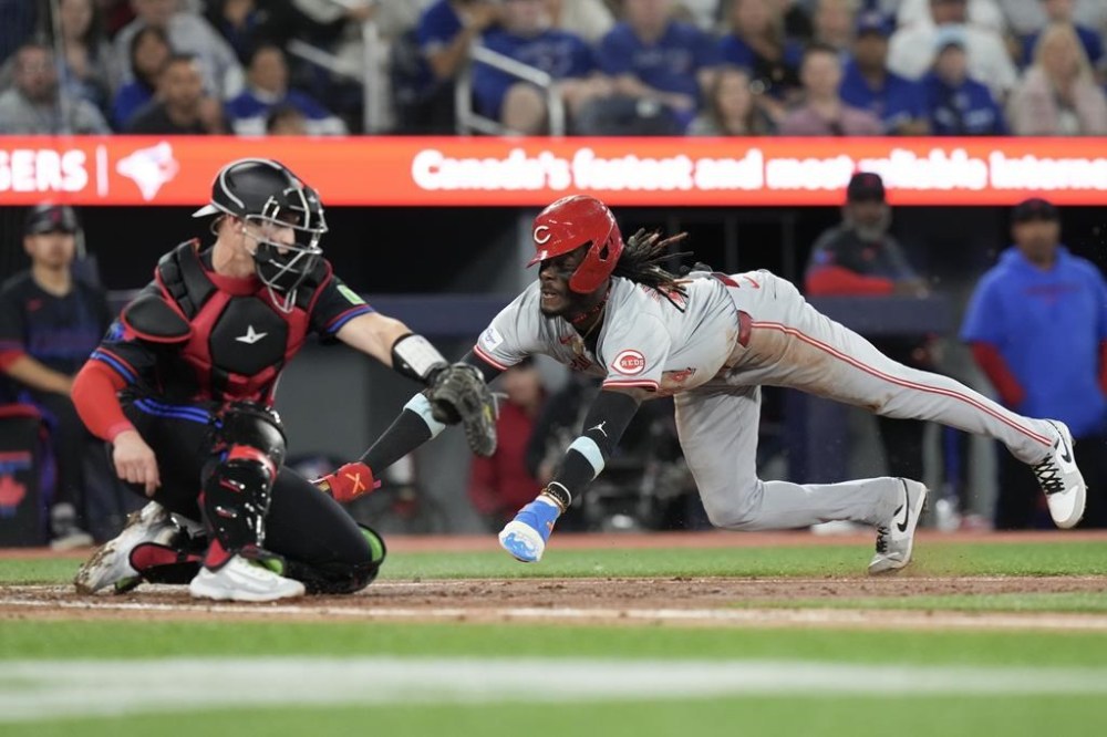 Cincinnati Reds Elly De La Cruz scores as he crosses the plate in front of Toronto Blue Jays catcher Brian Serven during fifth inning Interleague MLB baseball action in Toronto on Wednesday Aug. 21, 2024. THE CANADIAN PRESS/Chris Young