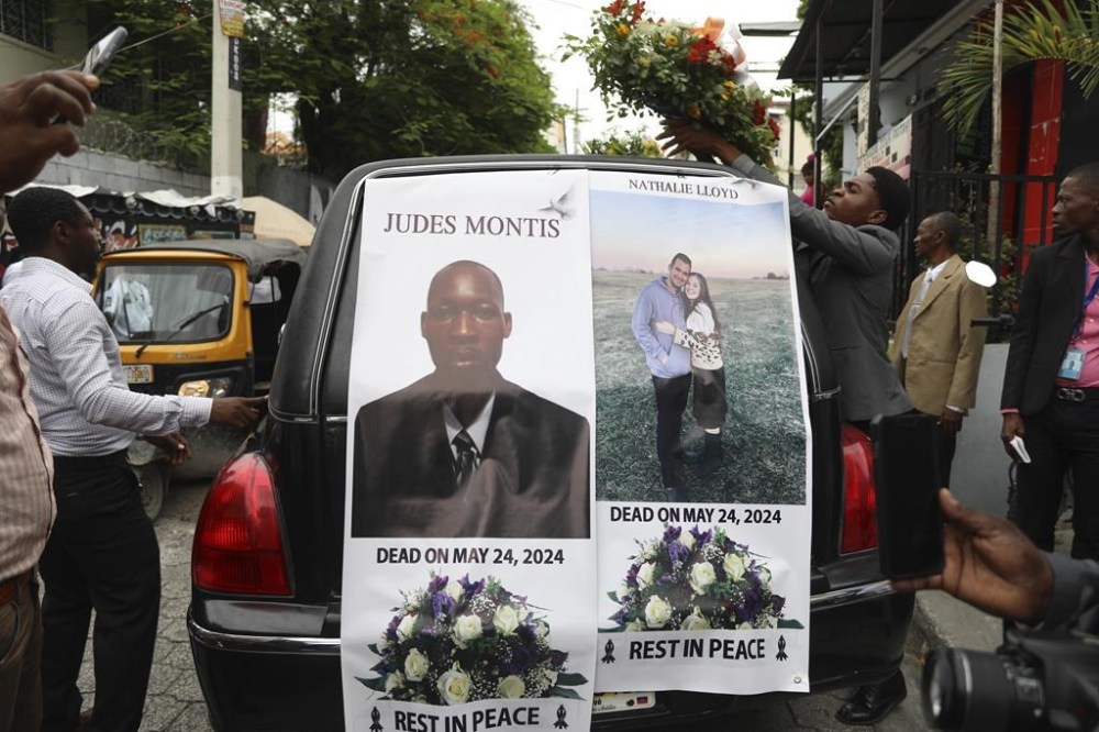 FILE - A funeral procession for mission director Judes Montis, killed by gangs alongside two of his U.S. missionary members, makes its way to the cemetery after his funeral ceremony in Port-au-Prince, Haiti, May 28, 2024. The service also honored the lives of Davy and Natalie Lloyd, featured on the photo on the back of the hearse, a married couple in their early 20s who was with Montis when gunmen ambushed them late May 23, as they left a youth group activity held at a local church. (AP Photo/Odelyn Joseph, File)