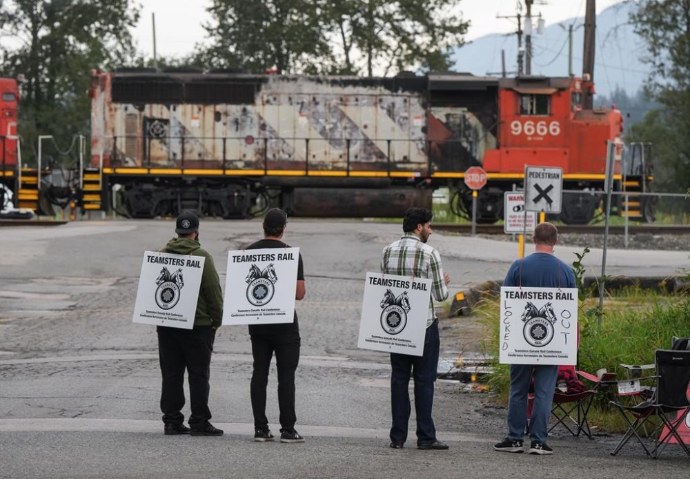 Locked-out Canadian National Railway workers stand at a picket line as locomotives are moved by management at CN Rail's Thornton Yard, in Surrey, B.C., on Thursday, August 22, 2024. On Thursday, Labour Minister Steven MacKinnon asked the Canada Industrial Relations Board to impose binding arbitration on the country's two main railways and their employees amid a work stoppage. THE CANADIAN PRESS/Darryl Dyck