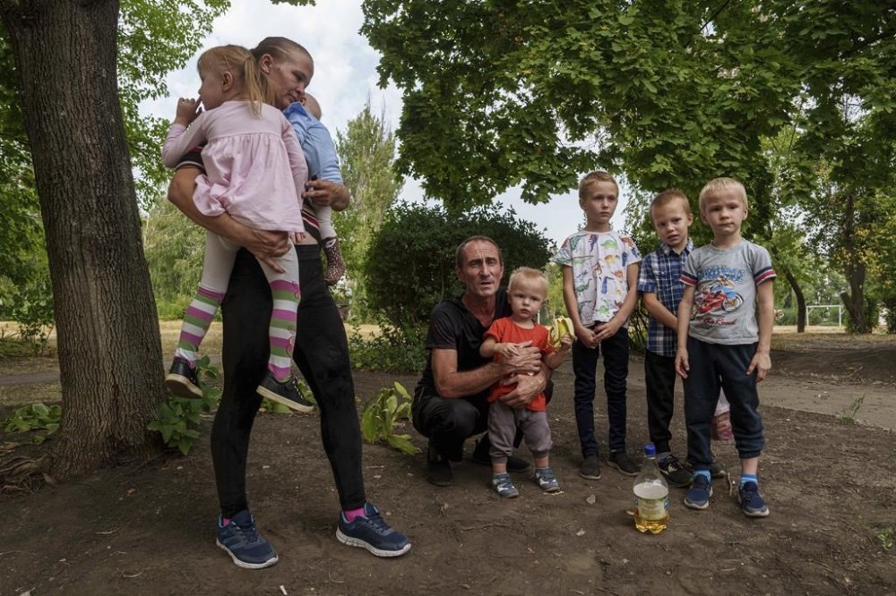 Iryna Belikova, 37, with her six children and husband, Ihor, wait for evacuation in Pokrovsk, Donetsk region, Ukraine, Friday, Aug. 23, 2024. (AP Photo/Evgeniy Maloletka)