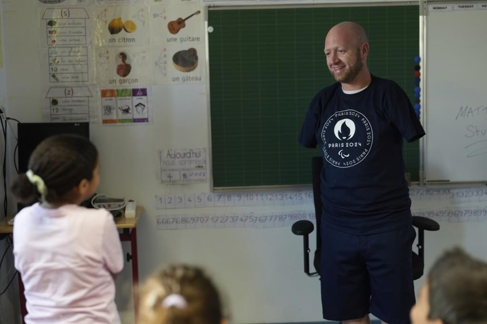 FILE - Archer Matt Stutzman of the United States talks to a pupil during a visit in a Paris school, in Paris, Oct. 4, 2023. Paralympians are not participating. They are competing. A number of athletes preparing for the Paris 2024 Paralympic Games proclaimed that message on their social feeds over the past few days, reminding the world that Olympians are not the only athletes coming to Paris looking for gold. (AP Photo/Thibault Camus, File)