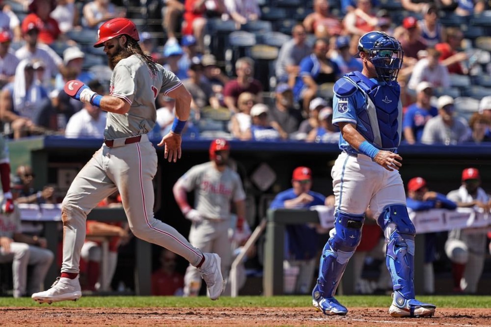 Philadelphia Phillies' Brandon Marsh runs past Kansas City Royals catcher Freddy Fermin to score on a ground out hit by Kyle Schwarber during the fourth inning of a baseball game Sunday, Aug. 25, 2024, in Kansas City, Mo. (AP Photo/Charlie Riedel)