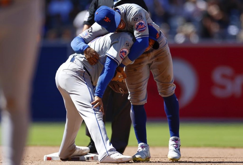 New York Mets shortstop Francisco Lindor, top, smiles with second baseman Jose Iglesias, bottom, after a force out against San Diego Padres' Jurickson Profar at second during the sixth inning of a baseball game, Sunday, Aug. 25, 2024, in San Diego. (AP Photo/Brandon Sloter)