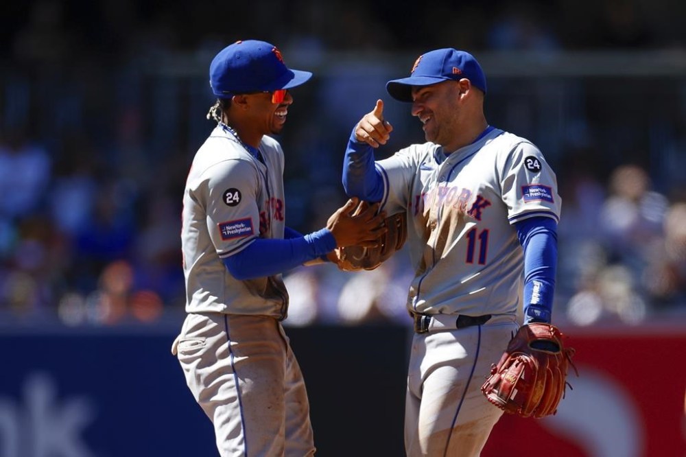 New York Mets shortstop Francisco Lindor, left, smiles with second baseman Jose Iglesias, right, after a force out against San Diego Padres' Jurickson Profar at second during the sixth inning of a baseball game, Sunday, Aug. 25, 2024, in San Diego. (AP Photo/Brandon Sloter)