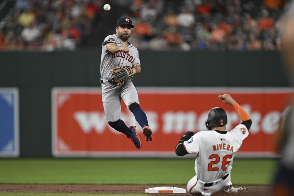 Houston Astros second baseman Jose Altuve, left, attempts to turn a double play after getting a force out against Baltimore Orioles' Emmanuel Rivera, right, on a ball hit by Gunnar Henderson during the third inning of a baseball game, Sunday, Aug. 25, 2024, in Baltimore. (AP Photo/Terrance Williams)