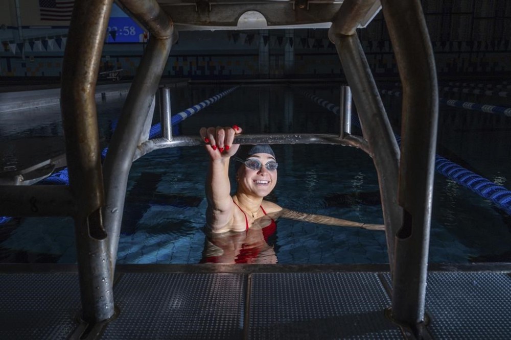 Paralympic swimmer Ali Truwit holds onto a starting platform while posing for photos, following practice at Chelsea Piers Athletic Club, Friday, Aug. 2, 2024, in Stamford, Conn. (AP Photo/Julia Nikhinson)
