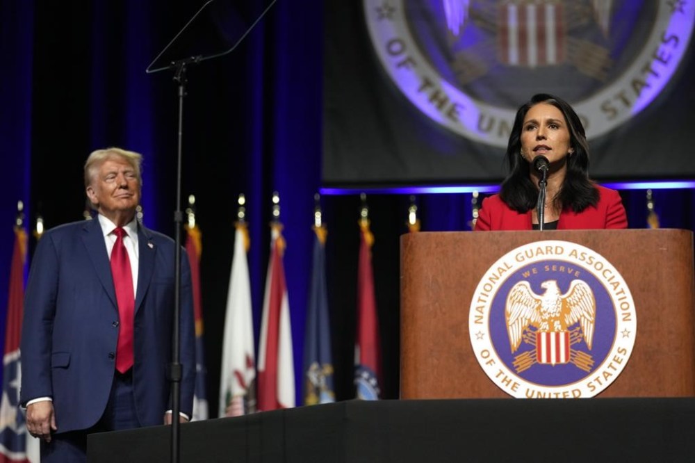 Republican presidential nominee former President Donald Trump, left, looks on as former Rep. Tulsi Gabbard of Hawaii, speaks at the National Guard Association of the United States' 146th General Conference, Monday, Aug. 26, 2024, in Detroit. (AP Photo/Carolyn Kaster)