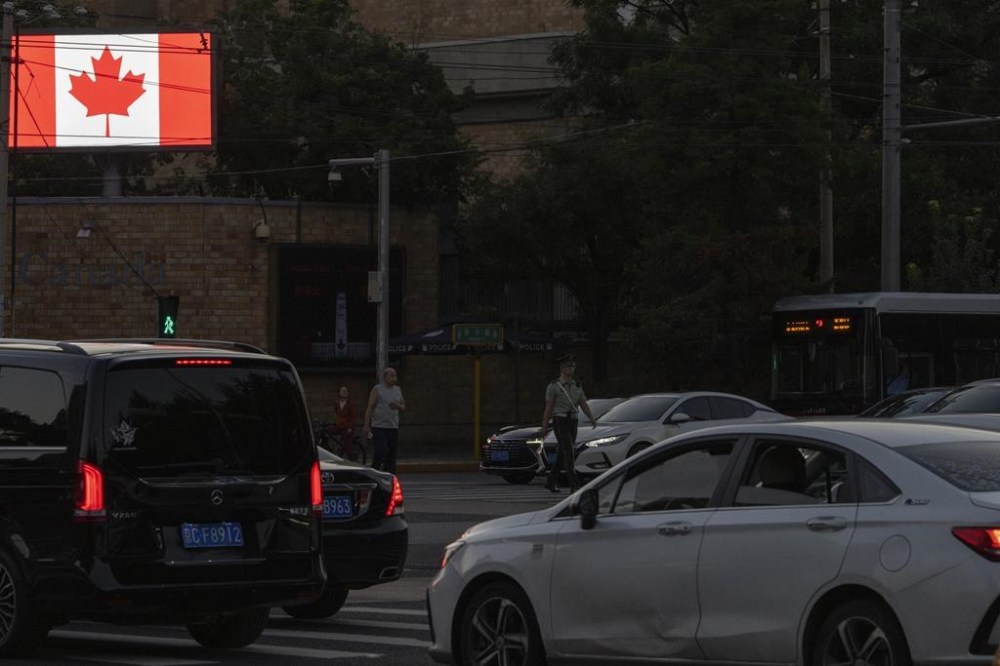 A Chinese paramlitary policeman crosses the road near vehicles outside the Canadian embassy in Beijing, Tuesday, Aug. 27, 2024. (AP Photo/Ng Han Guan)