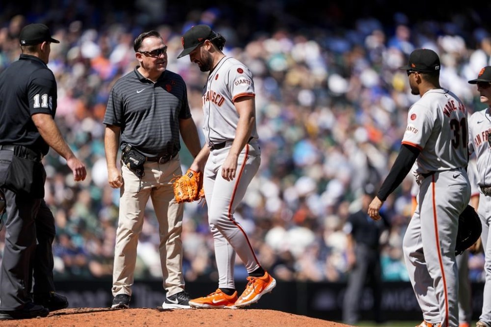 San Francisco Giants starting pitcher Robbie Ray, third from left, is checked by a trainer and later left with an injury during the fourth inning of a baseball game against the Seattle Mariners, Sunday, Aug. 25, 2024, in Seattle. (AP Photo/Lindsey Wasson)