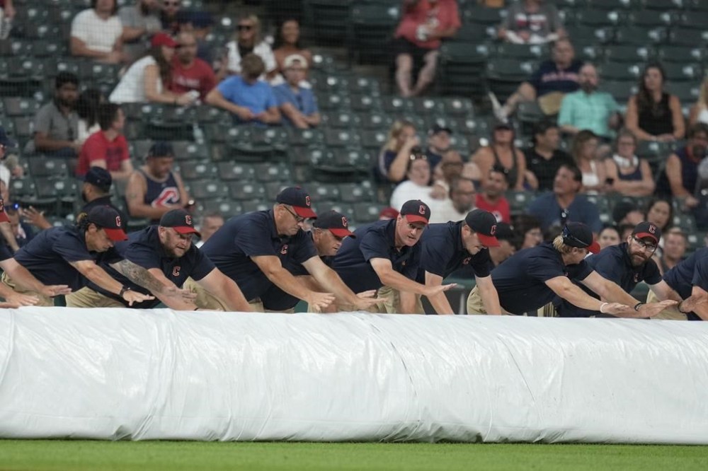 The Cleveland Guardians grounds crew rolls out the tarp for a rain delay after the fifth inning of a baseball game between the Kansas City Royals and the Cleveland Guardians, Tuesday, Aug. 27, 2024, in Cleveland. (AP Photo/Sue Ogrocki)