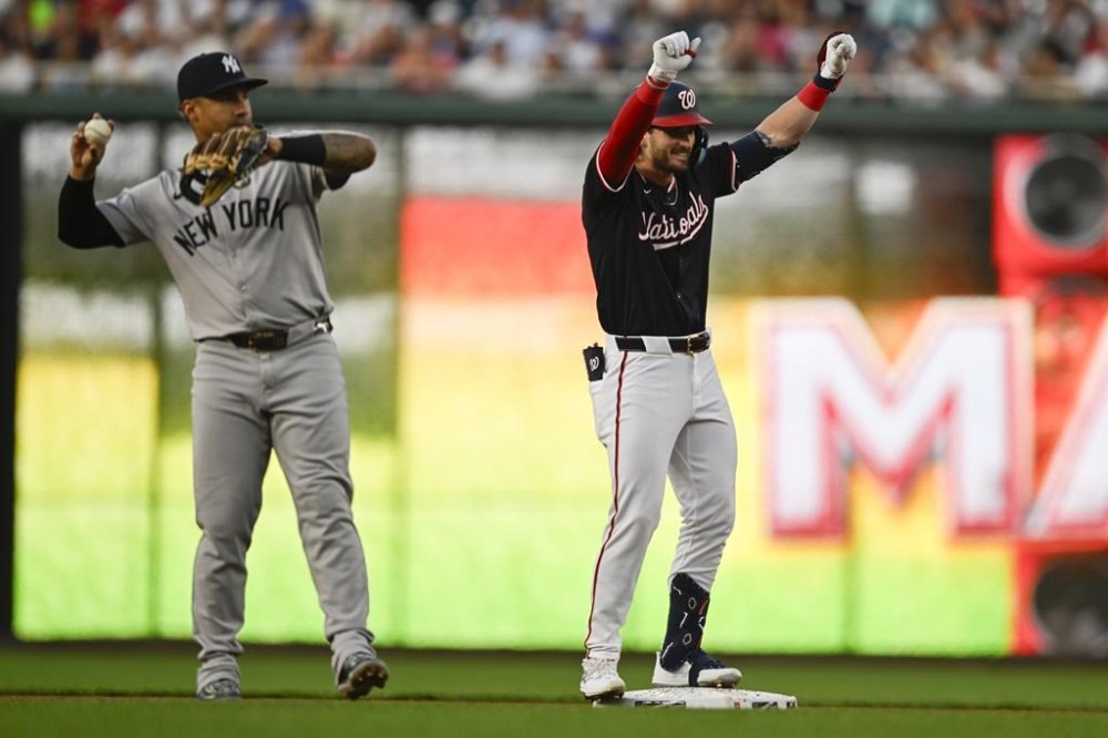 New York Yankees second baseman Gleyber Torres throws the ball as Washington Nationals' Dylan Crews celebrates his first major league hit at second base during the second inning of a baseball game, Tuesday, Aug. 27, 2024, in Washington. (AP Photo/John McDonnell)