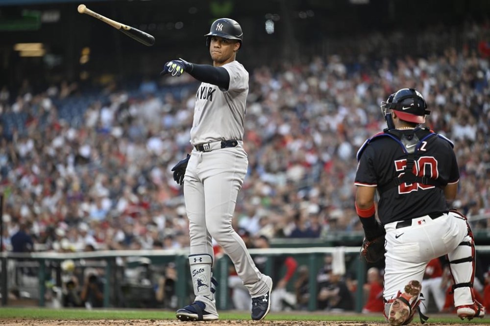 Washington Nationals catcher Keibert Ruiz, right, turn towards the dugout as New York Yankees' Juan Soto tosses his bat after striking outdoor in the final out of the third inning of a baseball game, Tuesday, Aug. 27, 2024, in Washington. (AP Photo/John McDonnell)