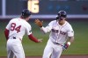Boston Red Sox's Jarren Duran, right, is congratulated by third base coach Kyle Hudson while rounding the bases on his solo home run ball during the first inning of a baseball game against the Toronto Blue Jays at Fenway Park, Tuesday, Aug. 27, 2024, in Boston. (AP Photo/Charles Krupa)