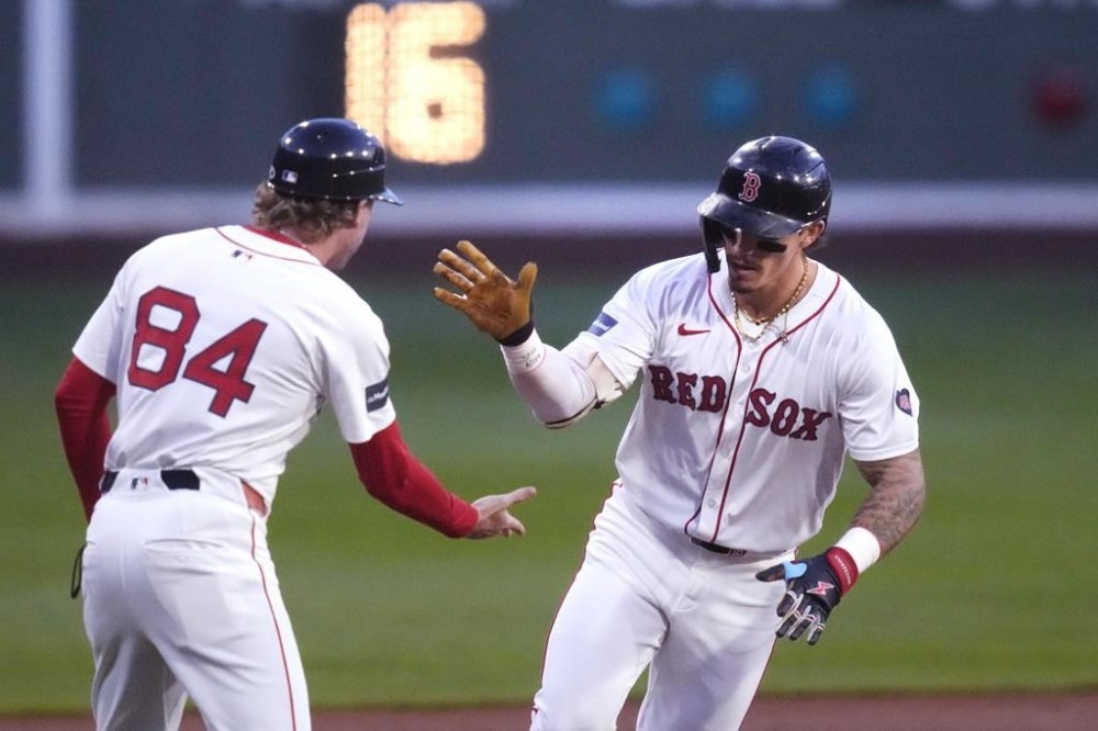 Boston Red Sox's Jarren Duran, right, is congratulated by third base coach Kyle Hudson while rounding the bases on his solo home run ball during the first inning of a baseball game against the Toronto Blue Jays at Fenway Park, Tuesday, Aug. 27, 2024, in Boston. (AP Photo/Charles Krupa)