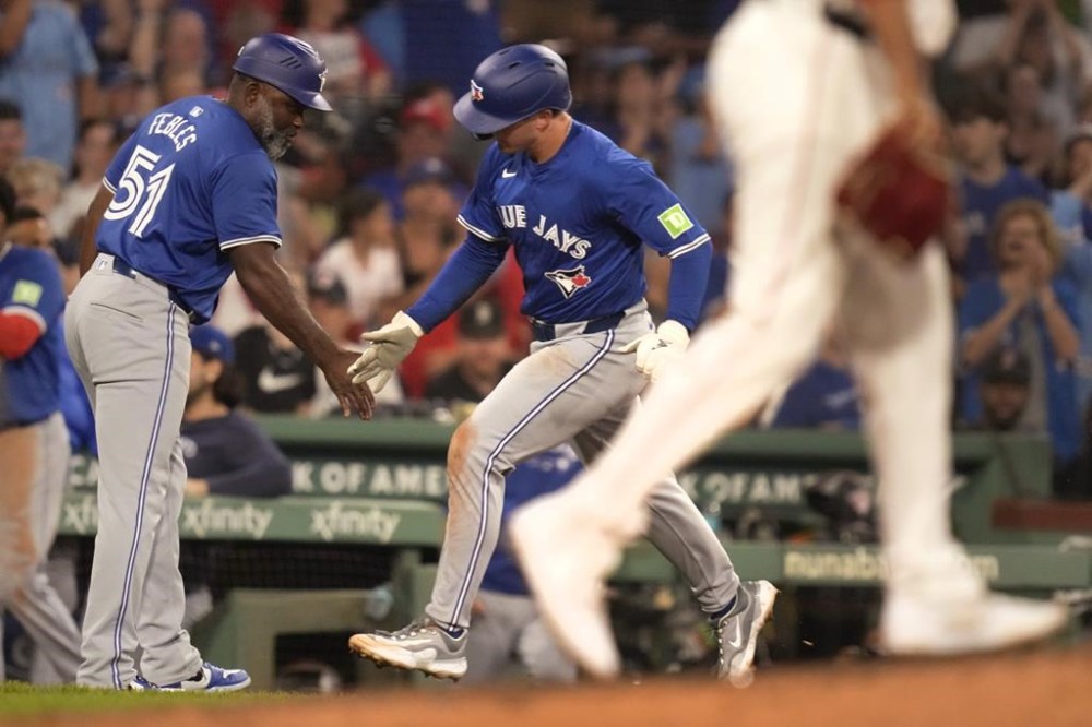 Toronto Blue Jays' Will Wagner is congratulated by third base coach Carlos Febles (51) after hitting a solo home run during the sixth inning of a baseball game against the Boston Red Sox at Fenway Park, Tuesday, Aug. 27, 2024, in Boston. (AP Photo/Charles Krupa)