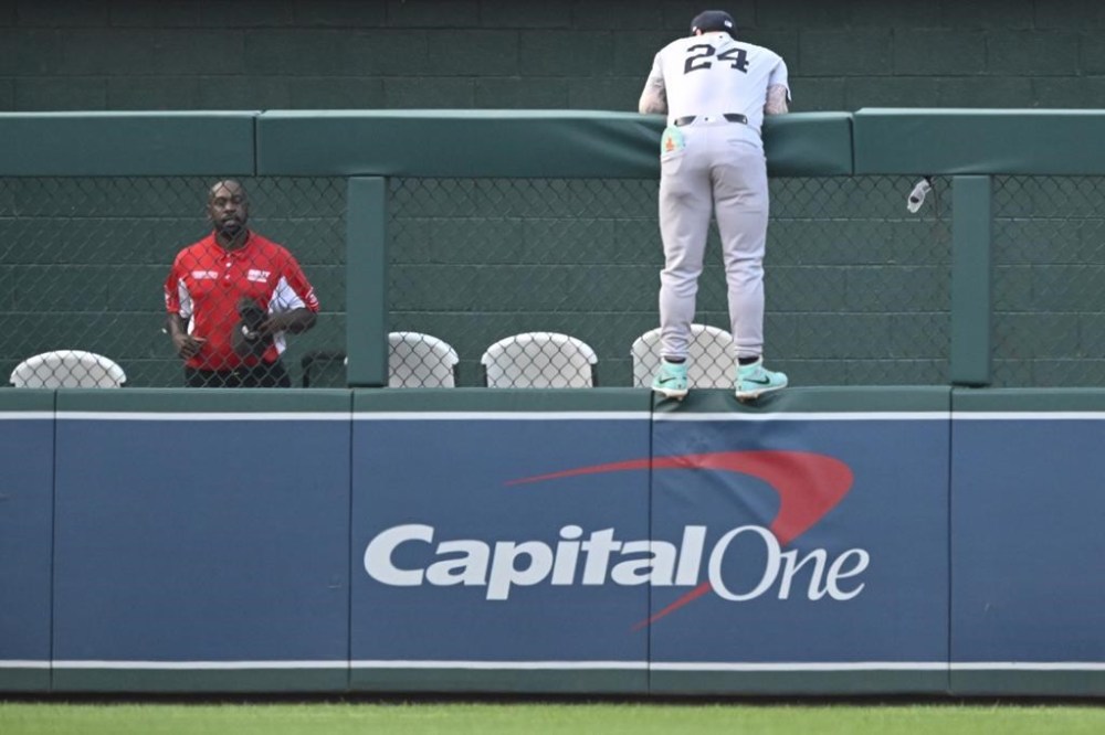New York Yankees left fielder Alex Verdugo jumps onto the fence in an effort to catch Washington Nationals' Dylan Crews solo home run during the first inning of a baseball game, Wednesday, Aug. 28, 2024, in Washington. (AP Photo/John McDonnell)