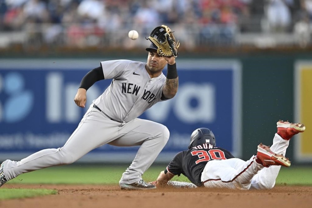 New York Yankees second baseman Gleyber Torres, left, catches a late throw as Washington Nationals' Jacob Young steals second during the second inning of a baseball game, Wednesday, Aug. 28, 2024, in Washington. (AP Photo/John McDonnell)