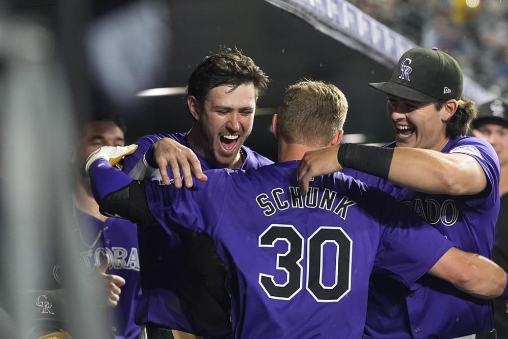 Colorado Rockies' Aaron Schunk, center, is congratulated by teammates Nolan Jones, left, and Michael Toglia after hitting his first home run of the major leagues, a solo shot off Miami Marlins starting pitcher Max Meyer, in the fifth inning of a baseball game Wednesday, Aug. 28, 2024, in Denver. (AP Photo/David Zalubowski)