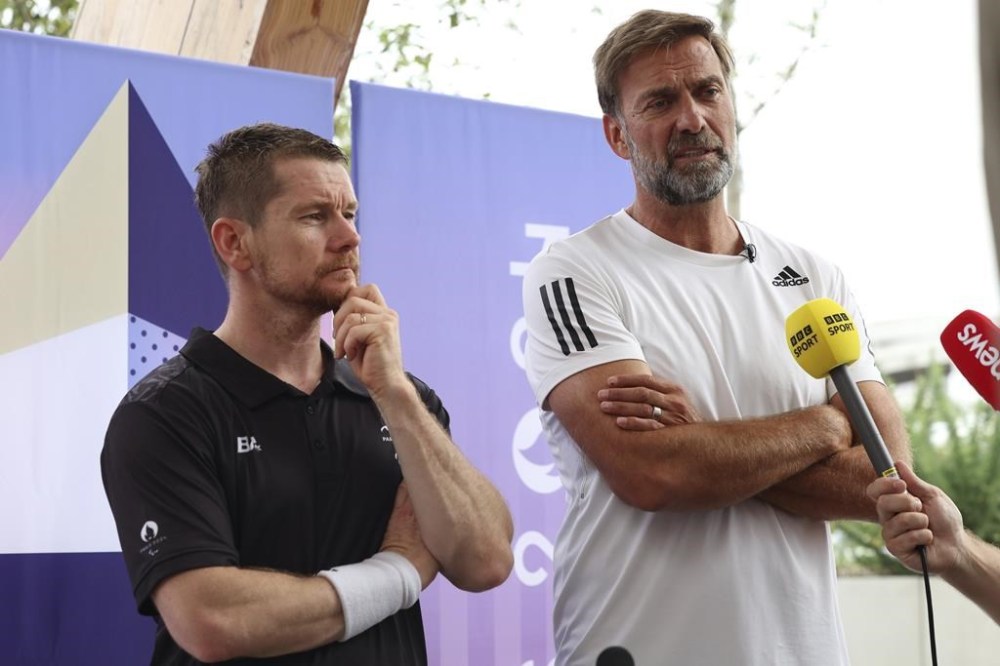 German football manager Jurgen Klopp, right, and para badminton player Wojtek Czyz discuss the results of Czyz's match in Porte La Chapelle Arena during the Paralympic Games on Wednesday, Aug. 28, 2024, in Paris. (AP Photo/Samantha Hurley).