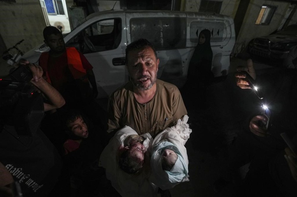 Osama al-Taweel holds the bodies of his grandchildren who were killed during an Israel airstrike in the Gaza Strip, as he arrives at the hospital morgue in Deir al Balah, Thursday, Aug. 29, 2024. (AP Photo/Abdel Kareem Hana)