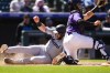 Miami Marlins' Jake Burger, left, scores on a double by Kyle Stowers as Colorado Rockies catcher Drew Romo fields the throw in the fourth inning of a baseball game Thursday, Aug. 29, 2024, in Denver. (AP Photo/David Zalubowski)