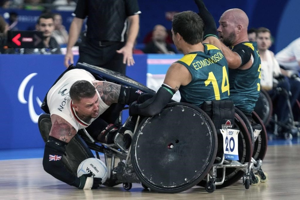Stuart Robinson of Great Britain, left, as he is blocked by Australians Andrew Edmondson, center, and Ryley Batt during the 2024 Paralympics Wheelchair Rugby match Australia against Great Britain at the Champs Mars Arena Thursday, Aug. 29, 2024, in Paris, France. (AP Photo/Michel Euler)