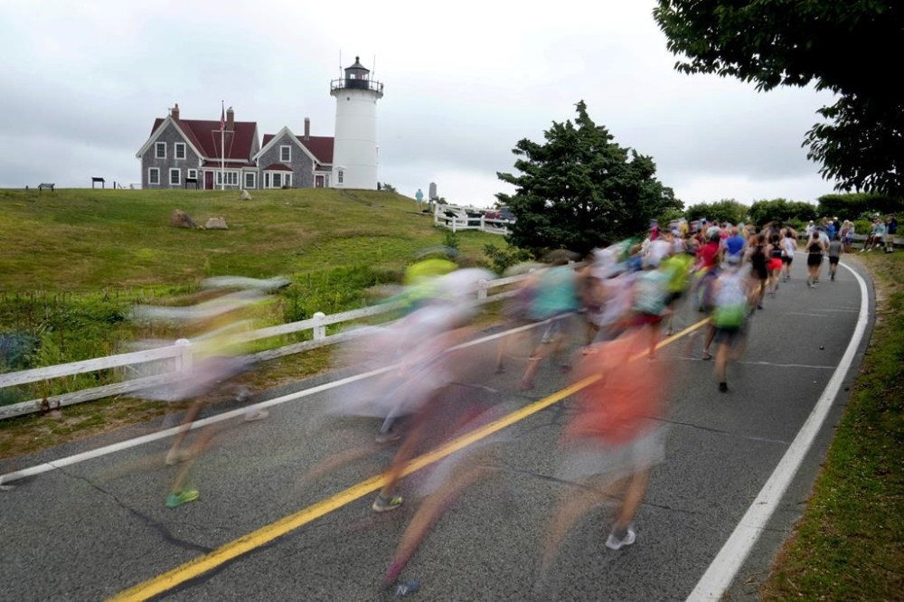 Runners pass Nobska Lighthouse near the 1-mile mark of the Falmouth Road Race, Sunday, Aug. 18, 2024, in Falmouth, Mass. (AP Photo/Jeff Roberson)