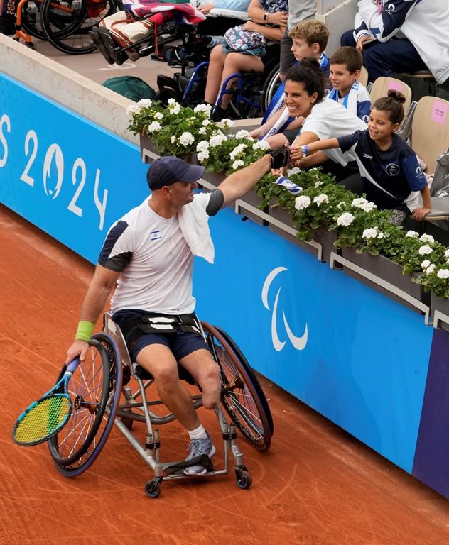 Israel's Adam Berdichevsky shakes hands with his wife Hila and his daughter during the 2024 Paralympics men's Wheelchair singles tennis tournament first round match against Italy's Luca Arca at Roland Garros Stadium in Paris, France, Friday Aug. 30, 2024. (AP Photo/Michel Euler)