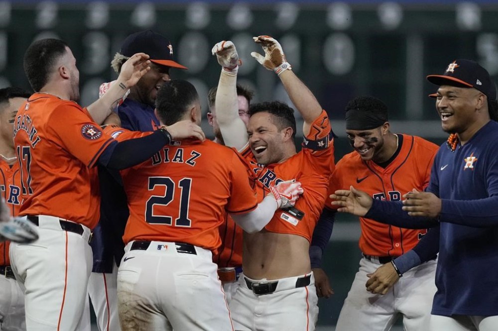 Houston Astros' Jose Altuve (27) is mobbed by his teammates after hitting a walk-off RBI double during the ninth inning of a baseball game against the Kansas City Royals, Friday, Aug. 30, 2024, in Houston. (AP Photo/Kevin M. Cox)