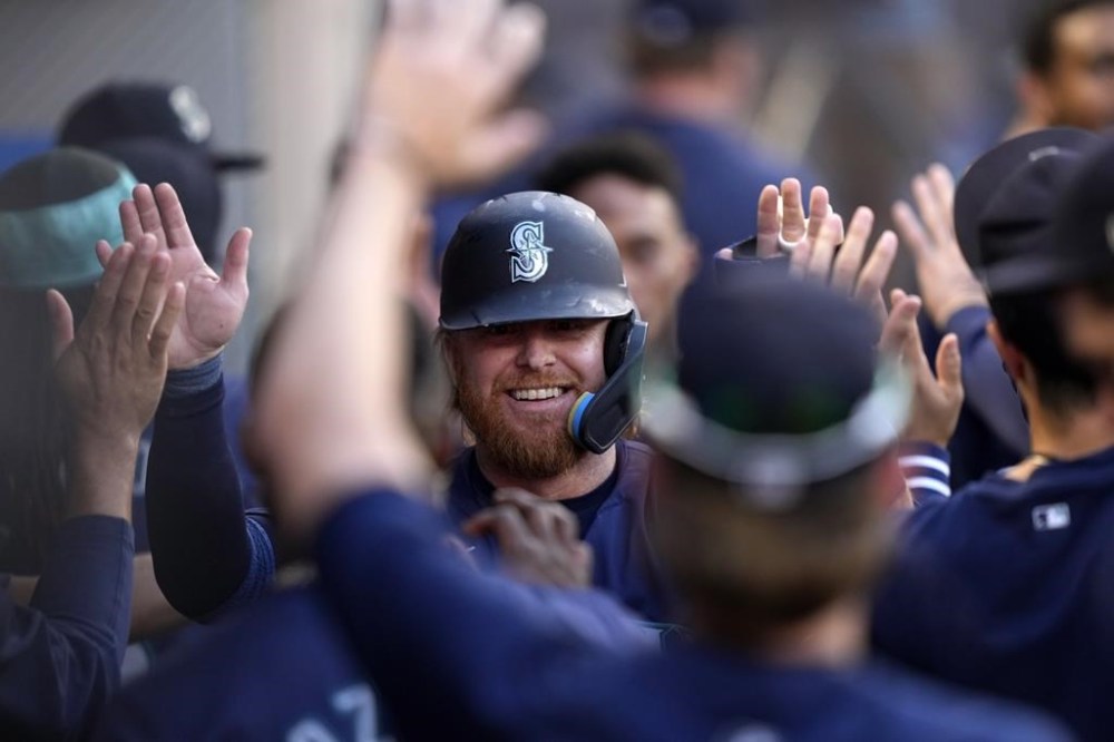 Seattle Mariners' Justin Turner is congratulated by teammates in the dugout after scoring on a double by Mitch Garver during the first inning of a baseball game against the Los Angeles Angels Friday, Aug. 30, 2024, in Anaheim, Calif. (AP Photo/Mark J. Terrill)