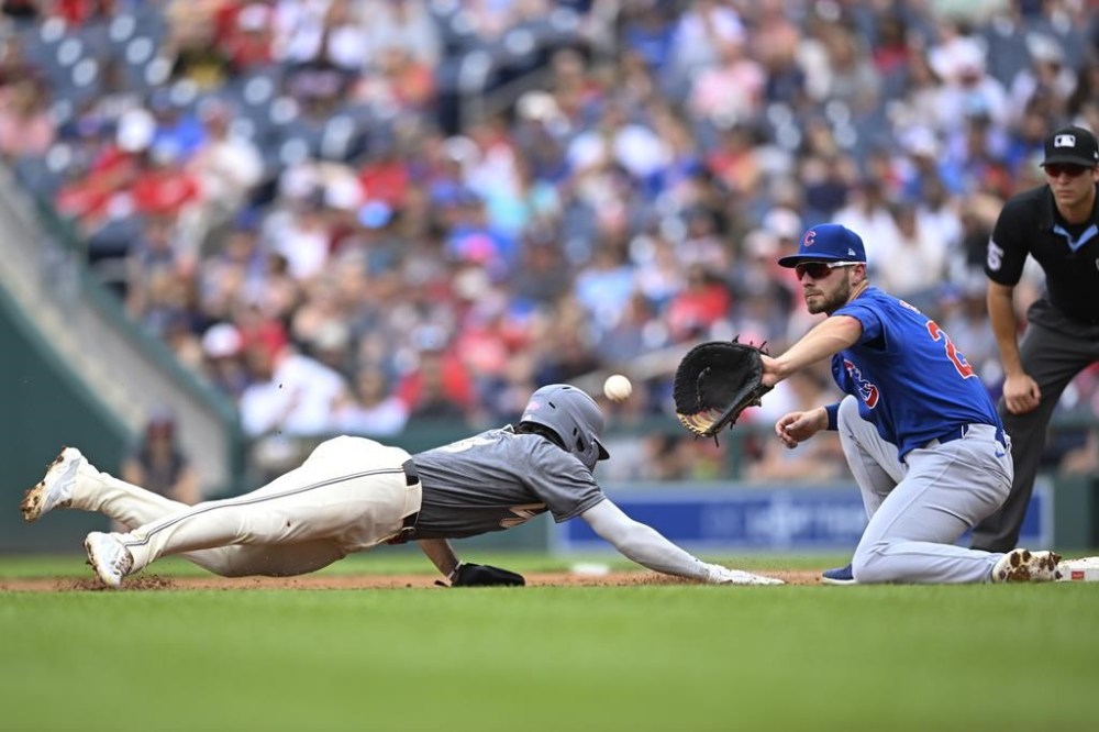 Washington Nationals' Jose Tena, left, is safe as he beats the pickoff throw to Chicago Cubs first baseman Michael Busch during the second inning of a baseball game Saturday, Aug. 31, 2024, in Washington. (AP Photo/John McDonnell)