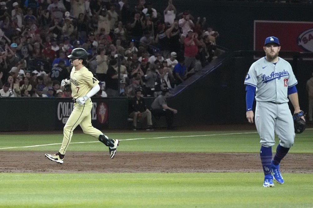 Arizona Diamondbacks' Corbin Carroll (7) rounds the bases after hitting a home run as Los Angeles Dodgers third baseman Max Muncy, right, walks to the mound to check on Dodgers pitcher Clayton Kershaw during the second inning of a baseball game Friday, Aug. 30, 2024, in Phoenix. (AP Photo/Ross D. Franklin)
