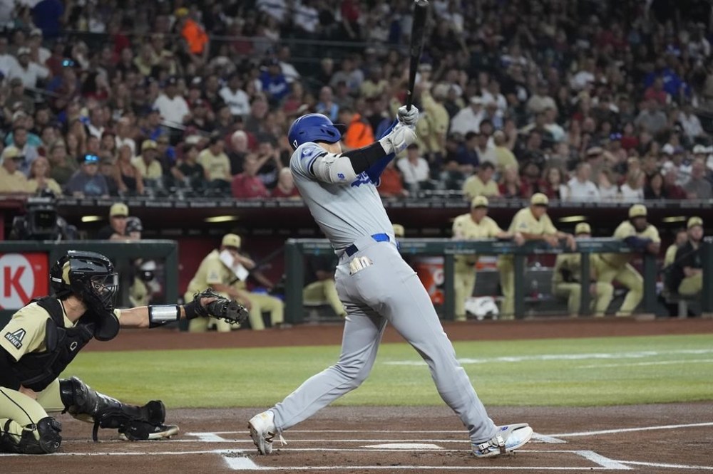 Los Angeles Dodgers designated hitter Shohei Ohtani, right, of Japan, connects for a home run as Arizona Diamondbacks catcher Adrian Del Castillo, left, looks on during the first inning of a baseball game Saturday, Aug. 31, 2024, in Phoenix. (AP Photo/Ross D. Franklin)