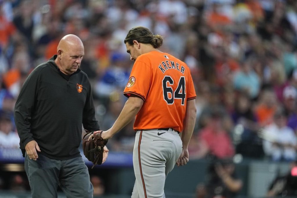 Baltimore Orioles starting pitcher Dean Kremer, right, has his arm checked by a trainer after being hit by a ground ball off the bat of Colorado Rockies' Jordan Beck in the fourth inning of a baseball game Saturday, Aug. 31, 2024, in Denver. (AP Photo/David Zalubowski)