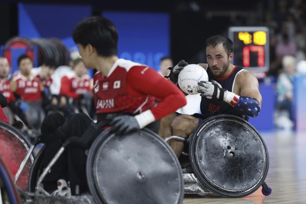 Chuck Aoki from the U.S. carries the ball during the U.S. vs Japan wheelchair rugby preliminary match during the Paralympic Games in Paris on Friday, Aug. 30, 2024. The U.S. Olympic and Paralympic Committee has launched a new project titled “Team USA Creators” to capture behind-the-scenes content at the Paralympics. Ten total athletes and influencers were selected to attend the event, have fun and raise disability visibility. Wheelchair rugby player Chuck Aoki is the only athlete competing and creating at these games. (AP Photo/Avni Trivedi)
