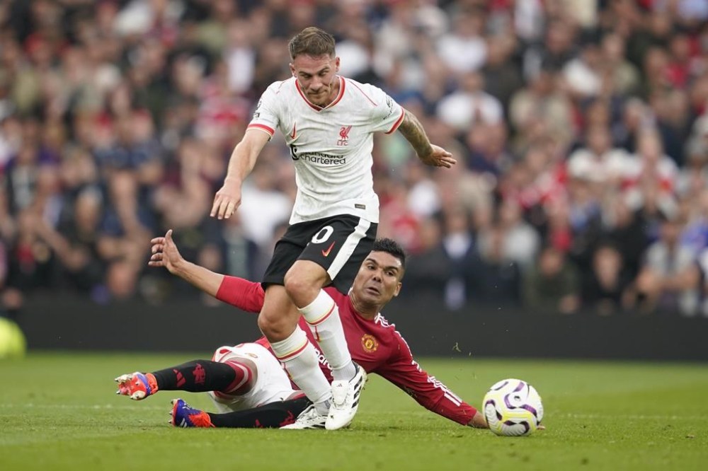 Liverpool's Alexis Mac Allister, centre, challenges for the ball with Manchester United's Casemiro during the English Premier League soccer match between Manchester United and Liverpool at Old Trafford, Sunday, Sept. 1, 2024, in Manchester, England. (AP Photo/Dave Thompson)