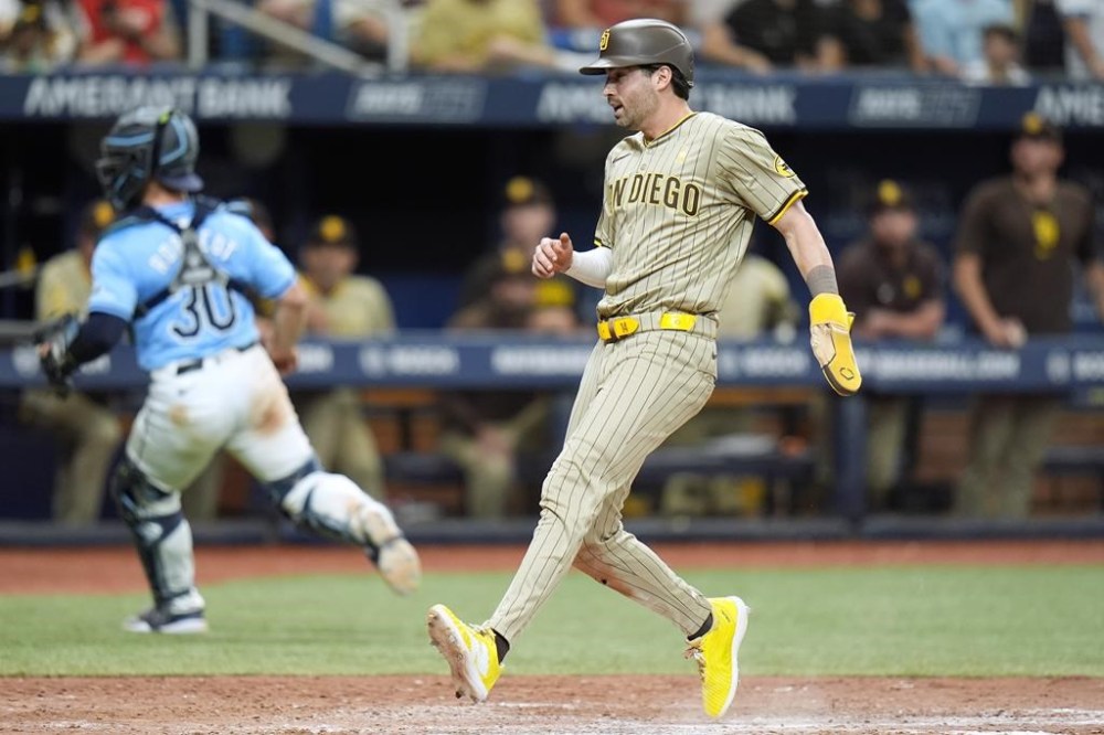 San Diego Padres' Tyler Wade scores on a sacrifice fly by Xander Bogaerts as Tampa Bay Rays catcher Ben Rortvedt (30) chases a wild throw during the ninth inning of a baseball game Sunday, Sept. 1, 2024, in St. Petersburg, Fla. (AP Photo/Chris O'Meara)