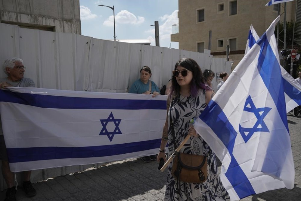 Mourners wave Israeli flags as they accompany the family of Israeli-American hostage Hersh Goldberg-Polin, who was killed in Hamas captivity in the Gaza Strip, on their way to his funeral in Jerusalem, Monday, Sept. 2, 2024. Israel said Sunday it recovered the bodies of six hostages, including Goldberg-Polin's. (AP Photo/Leo Correa)