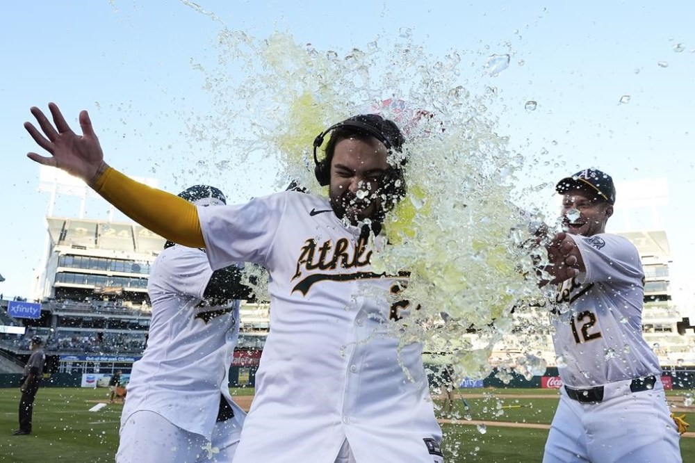Oakland Athletics' Shea Langeliers, center, is doused by teammates Lawrence Butler, left, and Max Schuemann, right, after hitting a winning solo home run against the Seattle Mariners in a baseball game Monday, Sept. 2, 2024, in Oakland, Calif. (AP Photo/Godofredo A. Vásquez)